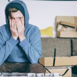 man covering face with both hands while sitting on bench