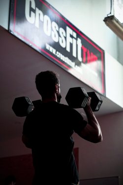 man in black t-shirt holding black dumbbell